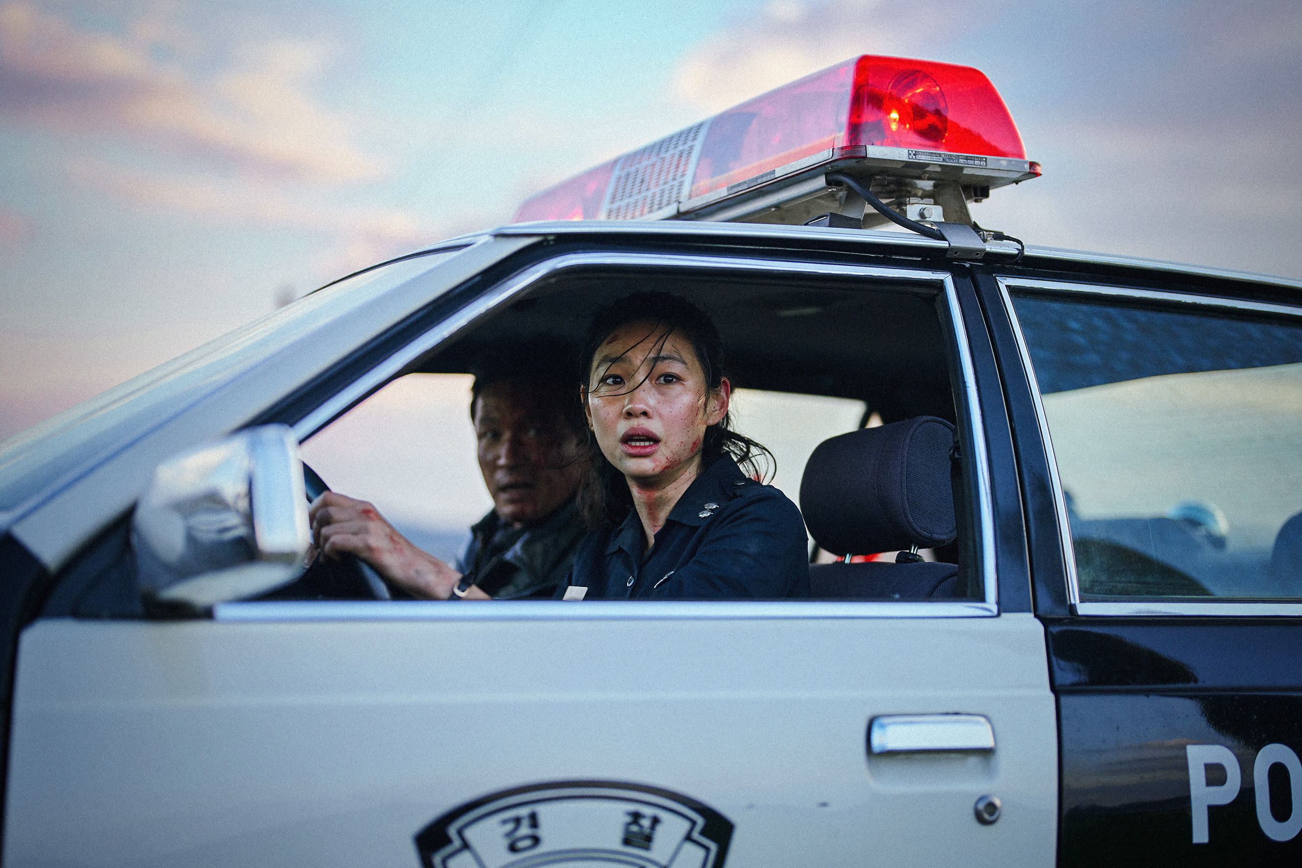 Hoyeon and Hwang Jung-min sit in a bloodied patrol car in Hope