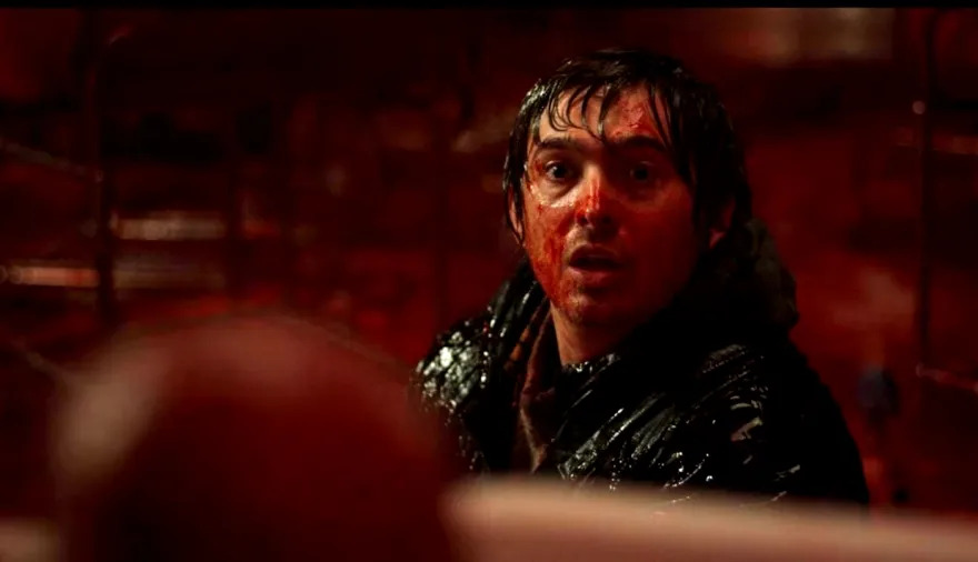Austin Abrams stands bloodied under red light in Resident Evil